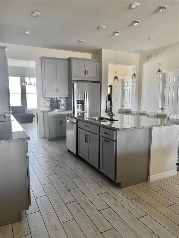 A kitchen with grey cabinets, a granite island, stainless steel appliances, and wood-look tile flooring — 9552 LAUNCH POINT ROAD, ORLANDO, FL