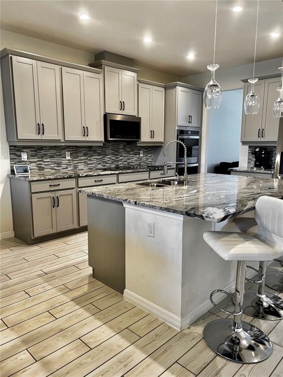 A kitchen features gray cabinets, granite countertops, a tiled backsplash, and a central island — 9552 LAUNCH POINT ROAD, ORLANDO, FL