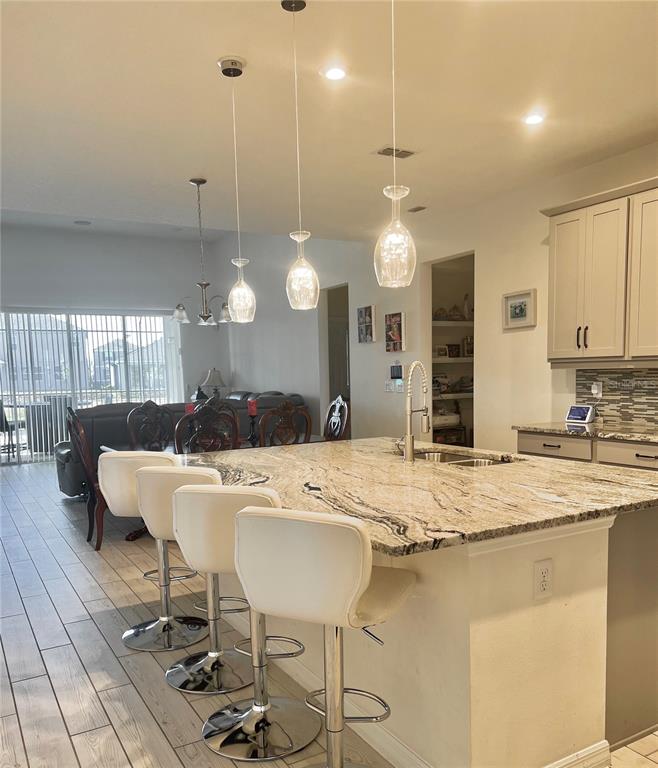 A kitchen island with bar stools sits in front of a dining area — 9552 LAUNCH POINT ROAD, ORLANDO, FL