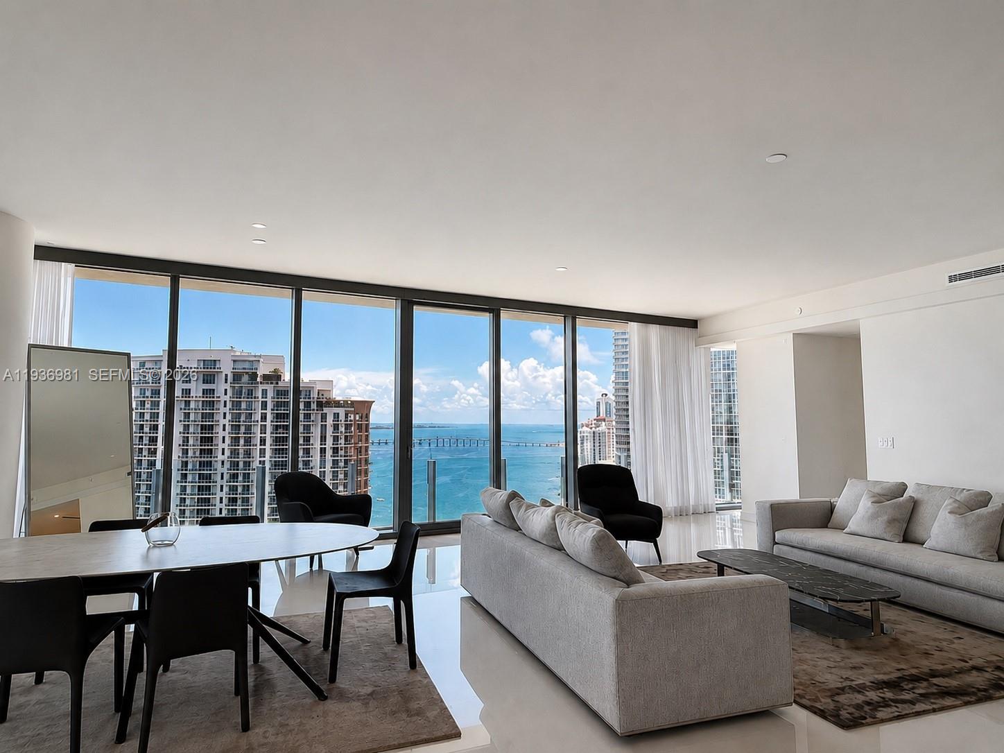 A modern living and dining area features floor-to-ceiling windows with expansive ocean and city views — 300 Biscayne Blvd Way # 3201, Miami FL 33130, MIAMI, FL