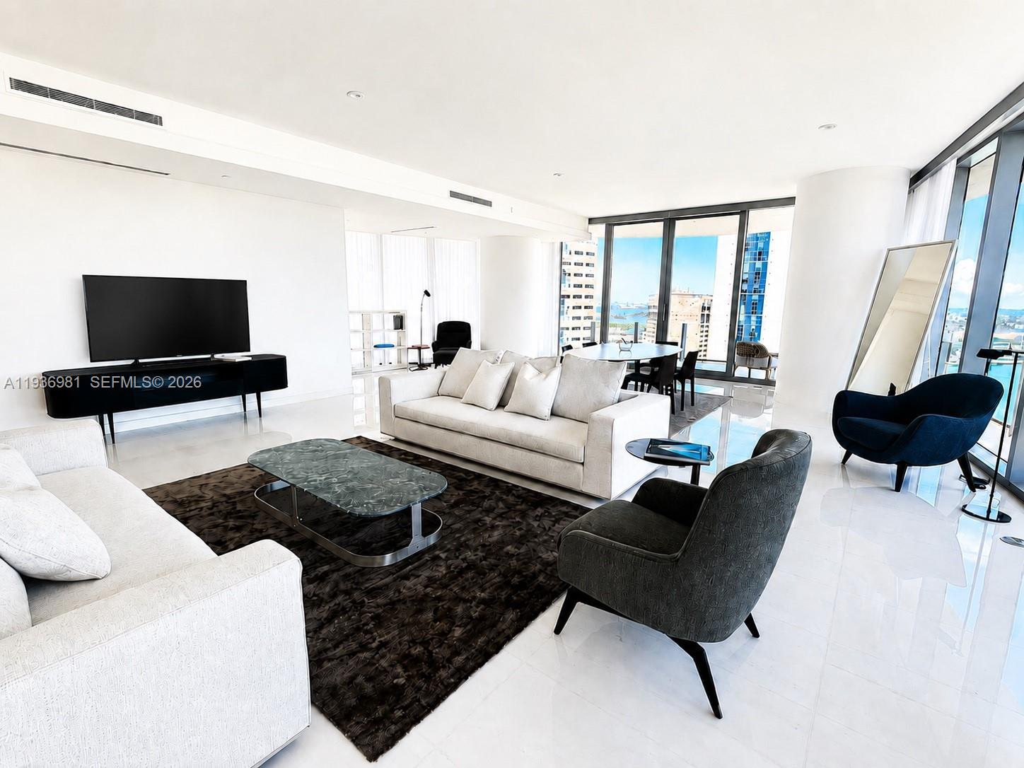 A bright, modern living room features white tile floors, a dark area rug, and floor-to-ceiling windows — 300 Biscayne Blvd Way # 3201, Miami FL 33130, MIAMI, FL