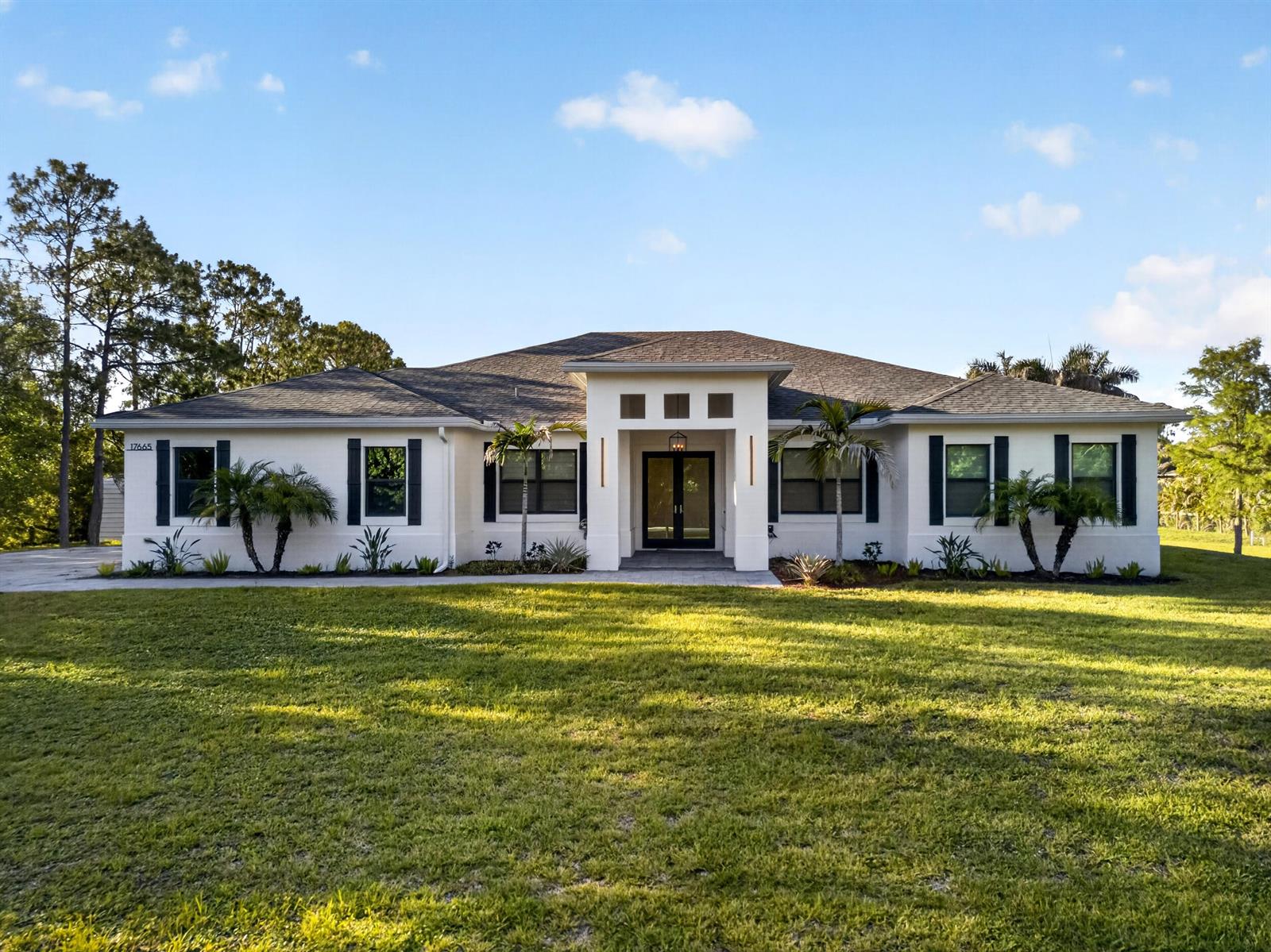 A single-story white house with a dark roof, black shutters, and a central entryway — 17655 44th Place N, FL 33470, FL