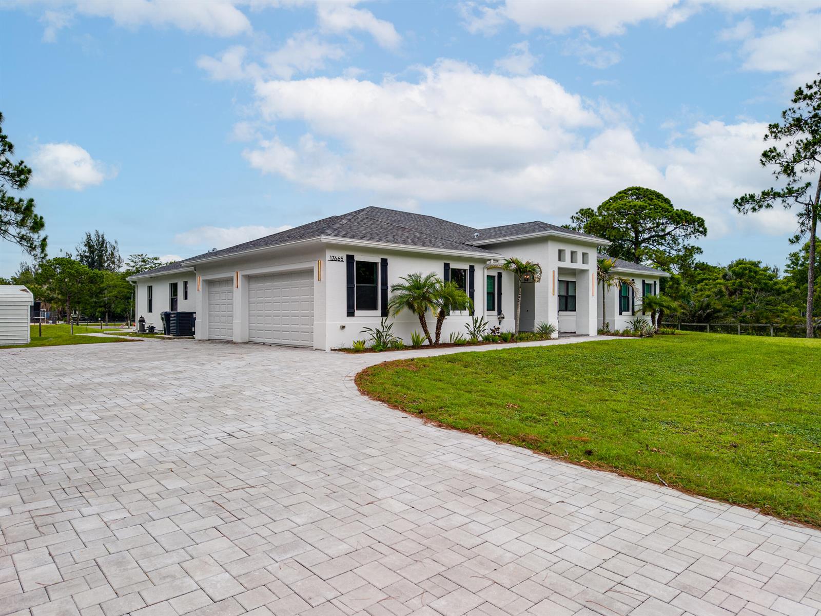 A white single-story house with a paver driveway and a three-car garage — 17655 44th Place N, FL 33470, FL