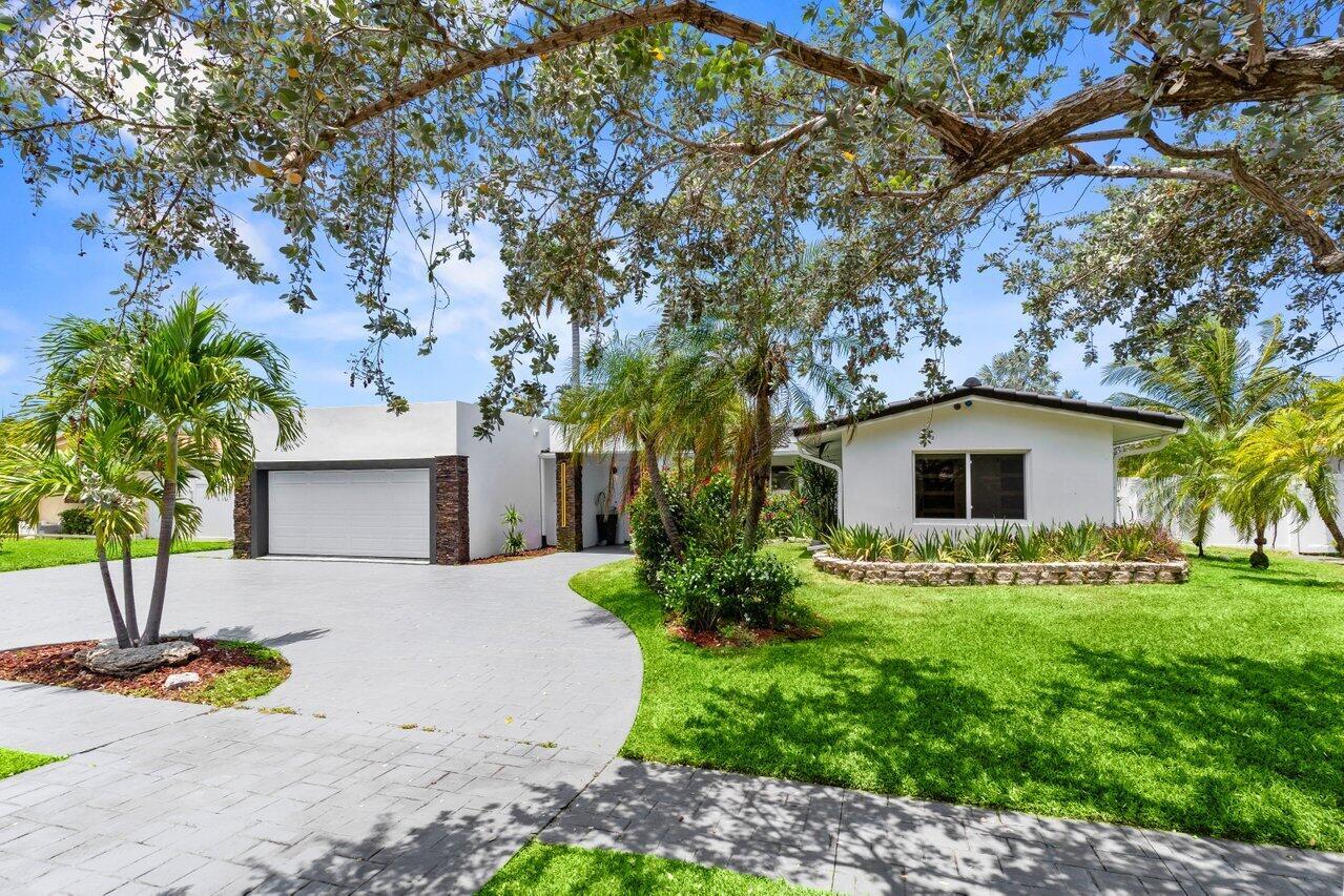 A white single-story house with a paved driveway, palm trees, and a green front lawn — 2611 NE 49 Street, Lighthouse Point FL 33064, LIGHTHOUSE POINT, FL