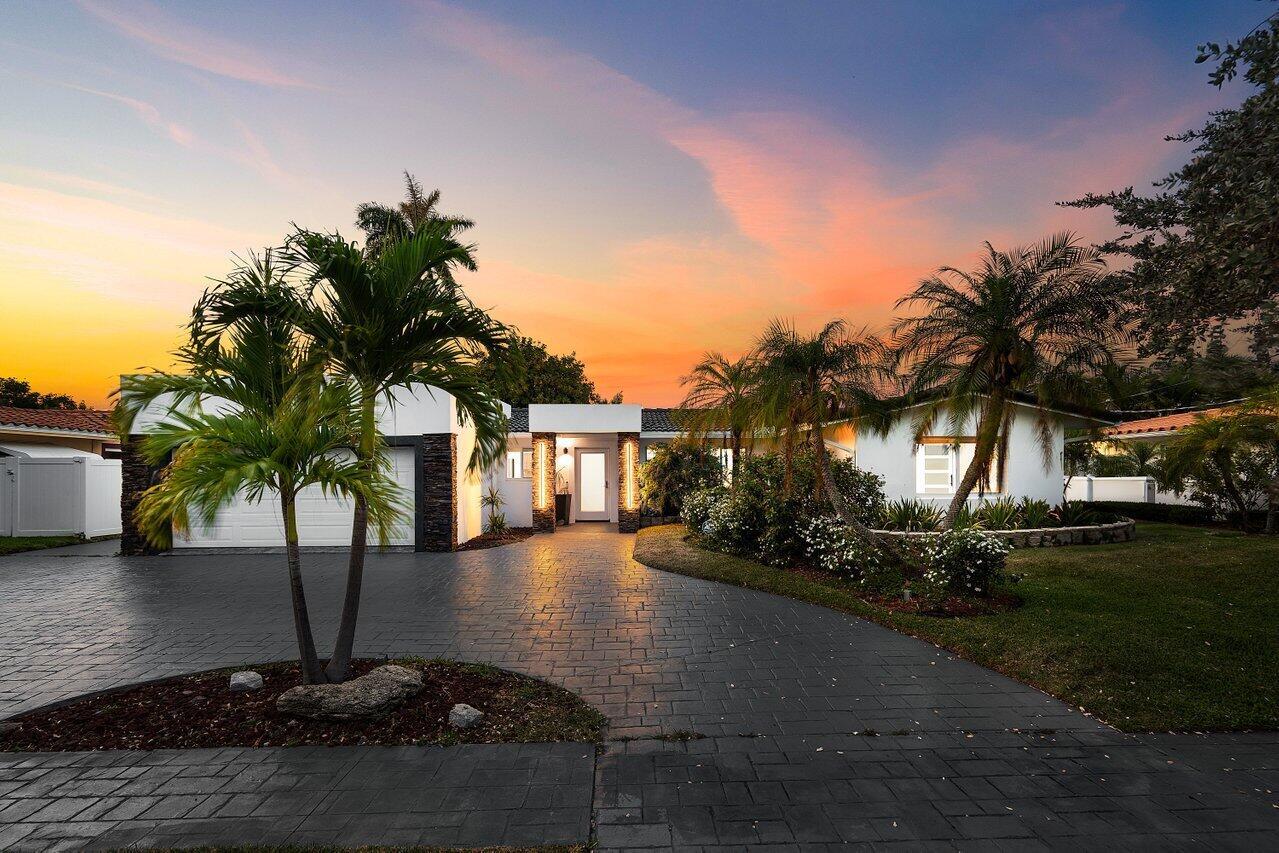 A single-story white house with a paved driveway, palm trees, and a two-car garage — 2611 NE 49 Street, Lighthouse Point FL 33064, LIGHTHOUSE POINT, FL