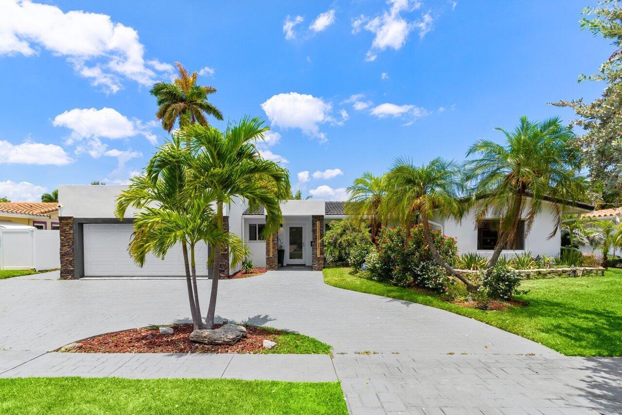 A white house exterior features a two-car garage, stone accents, and a paved driveway — 2611 NE 49 Street, Lighthouse Point FL 33064, LIGHTHOUSE POINT, FL