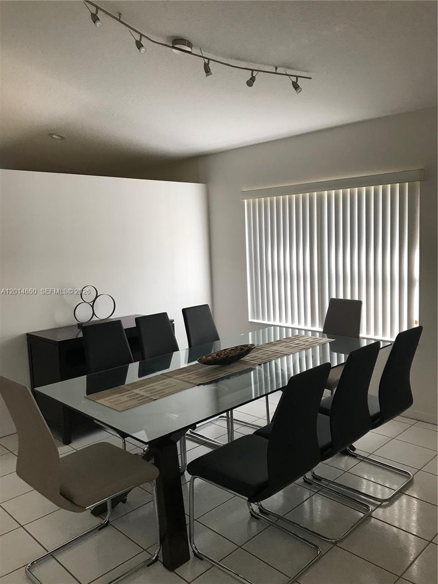 A dining room features a glass-topped table, eight chairs, a sideboard, and track lighting — 16654 SW 103rd Ln, Miami FL 33196, MIAMI, FL