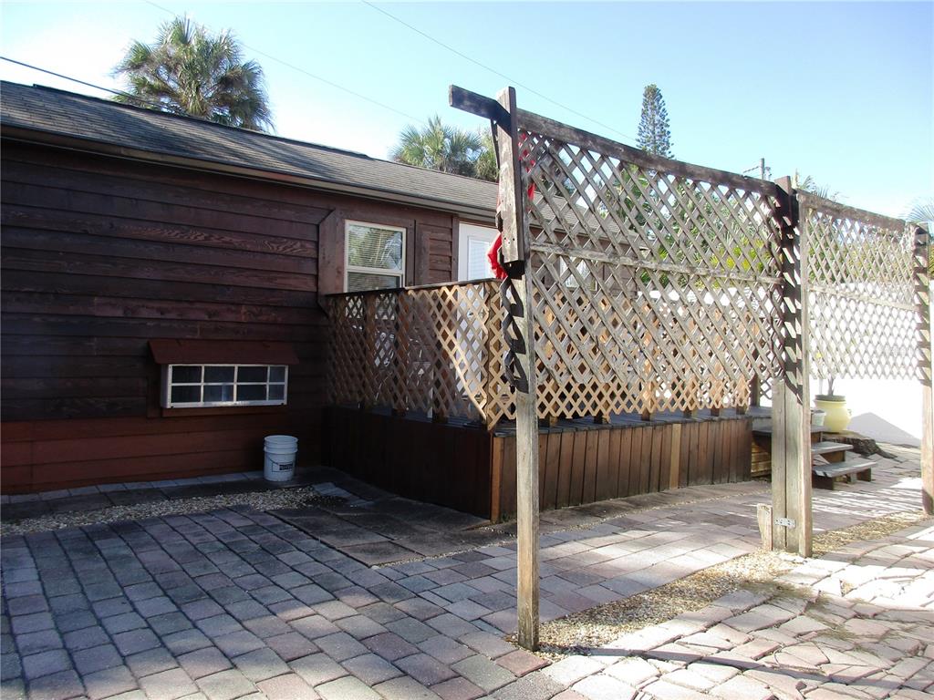 A wooden deck with lattice privacy screens sits beside a house with dark wood siding — 618 AVENIDA DE MAYO, SARASOTA, FL
