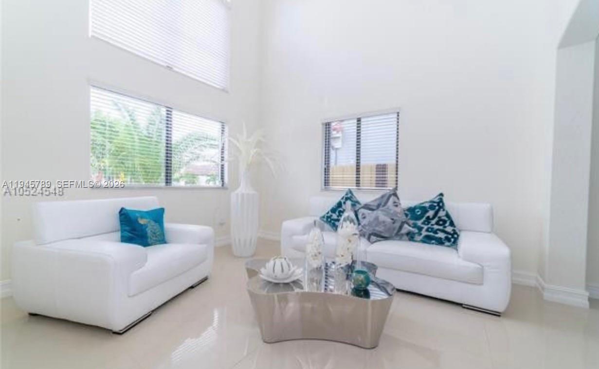A bright living room features white sofas, a metallic coffee table, and high ceilings — 16588 SW 44 Street, Kendall FL 33185, KENDALL, FL