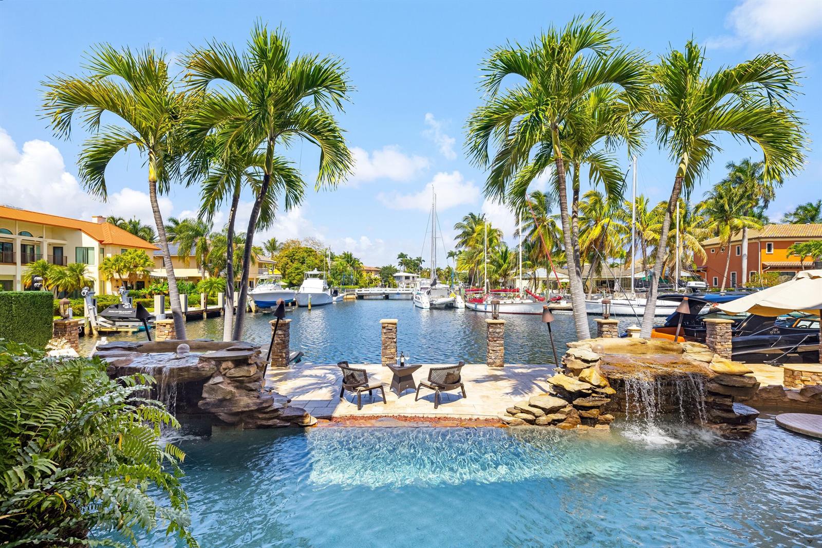 The exterior of a Mediterranean-style home features a stone entryway, arched doorway, and balcony — 2325 NE 27th Street, Lighthouse Point FL 33064, LIGHTHOUSE POINT, FL