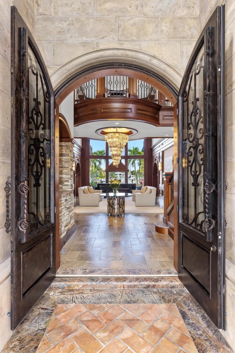 A hallway with arched wooden doorways, stone tile flooring, and textured gold-toned walls — 2325 NE 27th Street, Lighthouse Point FL 33064, LIGHTHOUSE POINT, FL