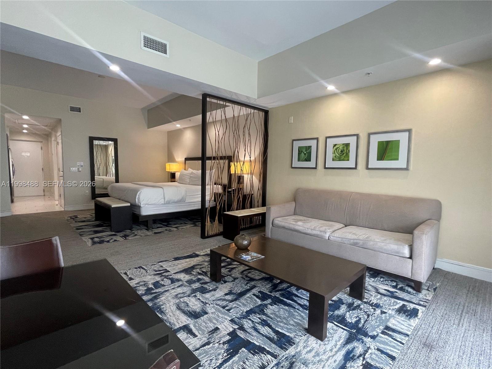 A hotel-style room features a bed, a sofa, a coffee table, and a decorative divider — 5300 NW 87th Ave # 1103, Doral FL 33178, DORAL, FL