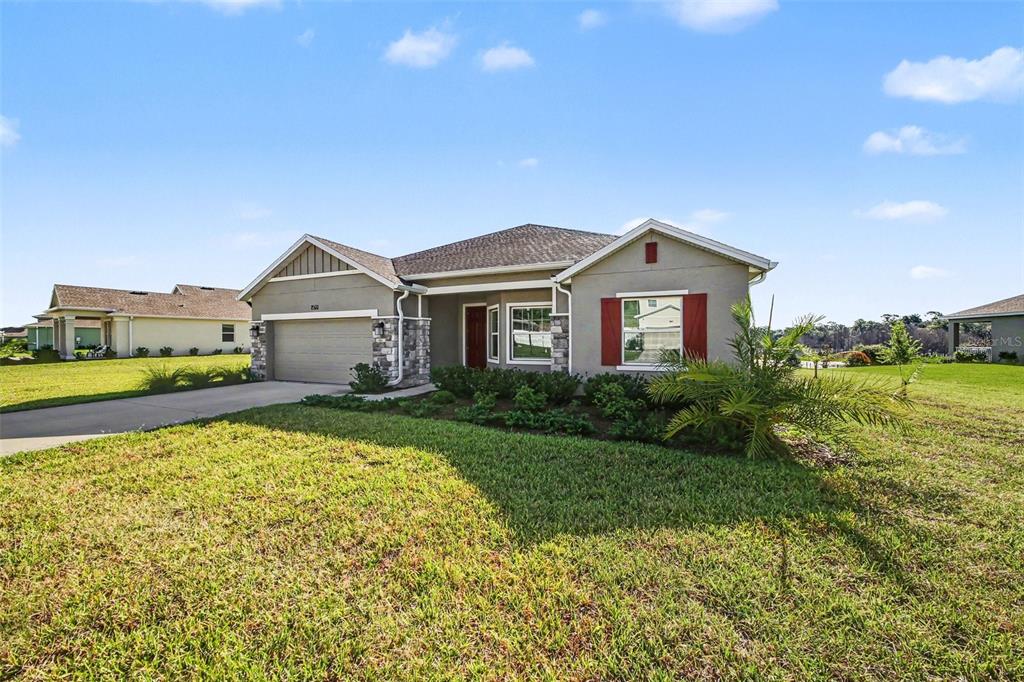 A single-story suburban house with a tan stucco exterior, stone accents, and a two-car garage — 6079 CLAYSTONE WAY, MOUNT DORA, FL