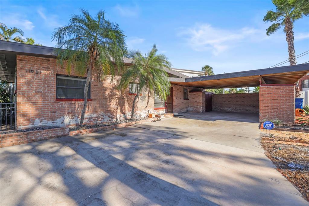 A brick house with a flat roof, a concrete driveway, and an attached carport — 11921 LAGOON LANE, TREASURE ISLAND, FL