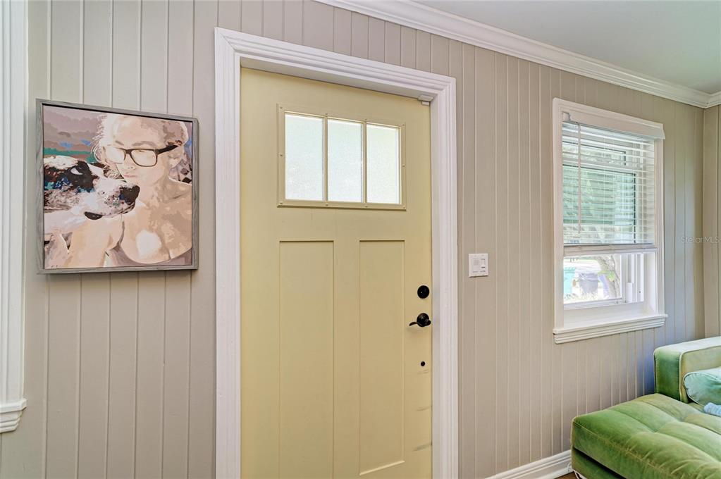 A light yellow door with a window sits between a framed painting and a window — 508 16TH AVENUE W, PALMETTO, FL
