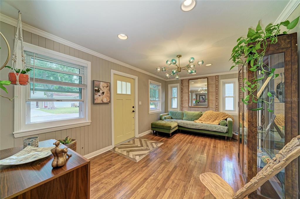 A living room with wood floors, a green sectional sofa, and a yellow front door — 508 16TH AVENUE W, PALMETTO, FL