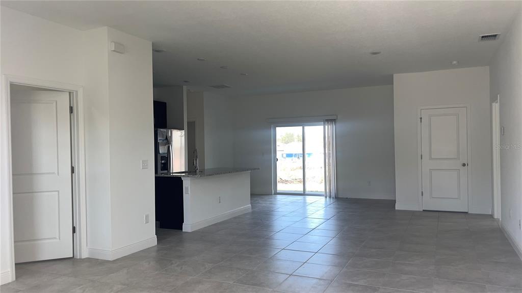 An open-concept kitchen and living area features tile flooring, white walls, and sliding glass doors — 16390 SW 17TH TERRACE ROAD, OCALA, FL