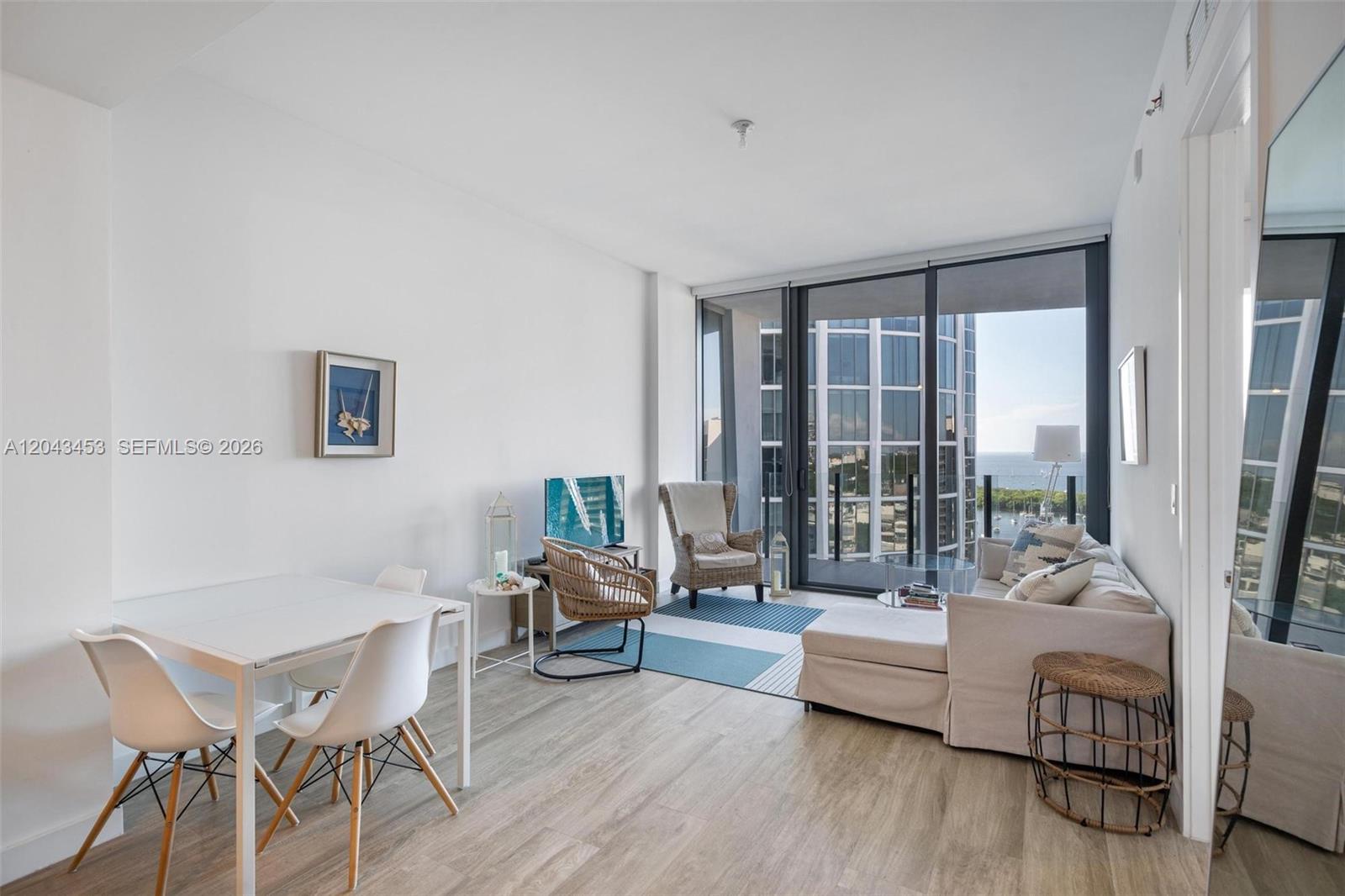 A living and dining area features light wood flooring, floor-to-ceiling windows, and a balcony view — 2831 S Bayshore Dr # 1603, Miami FL 33133, MIAMI, FL