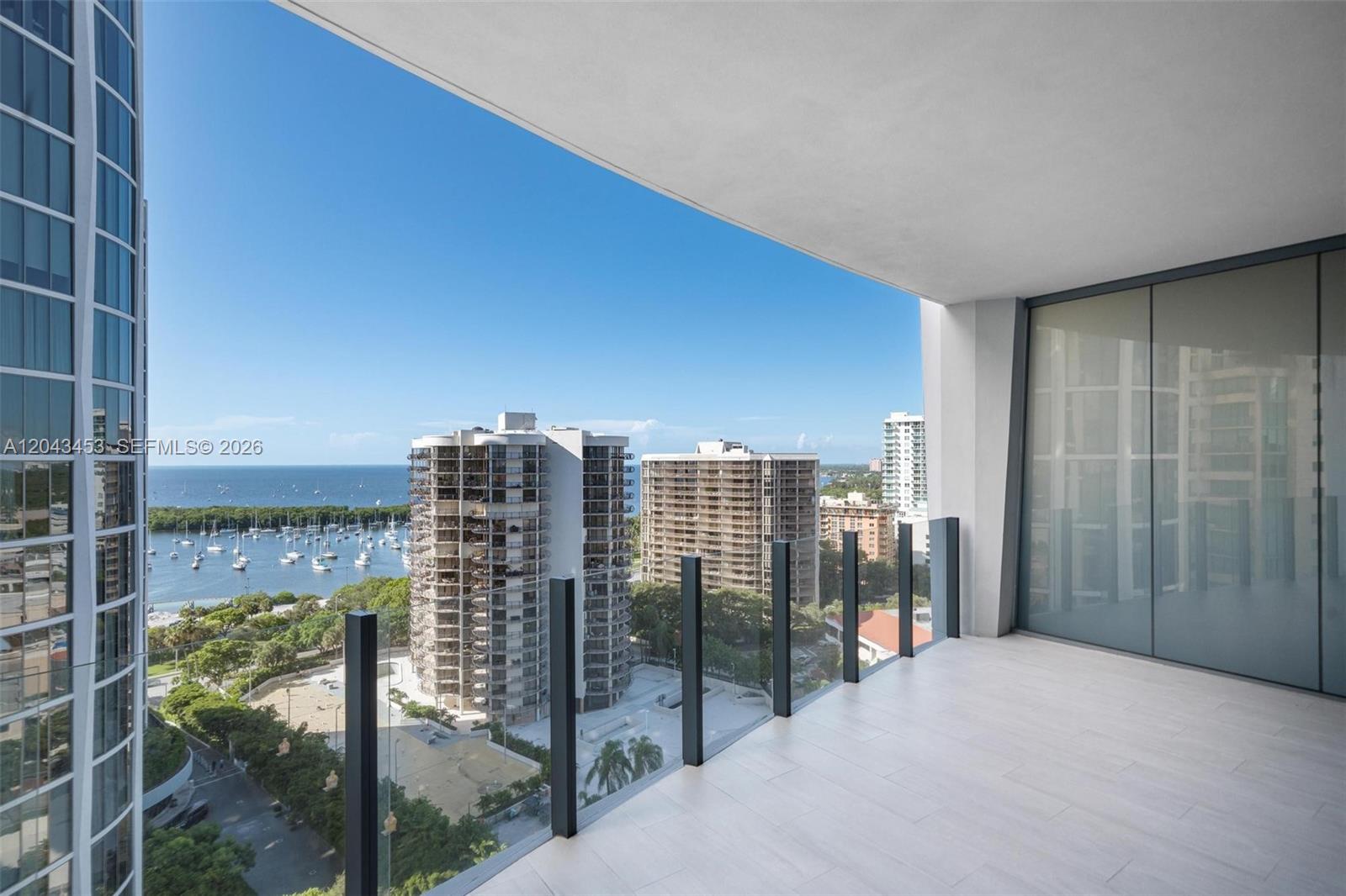 A modern balcony with glass railings overlooks a marina and high-rise buildings — 2831 S Bayshore Dr # 1603, Miami FL 33133, MIAMI, FL