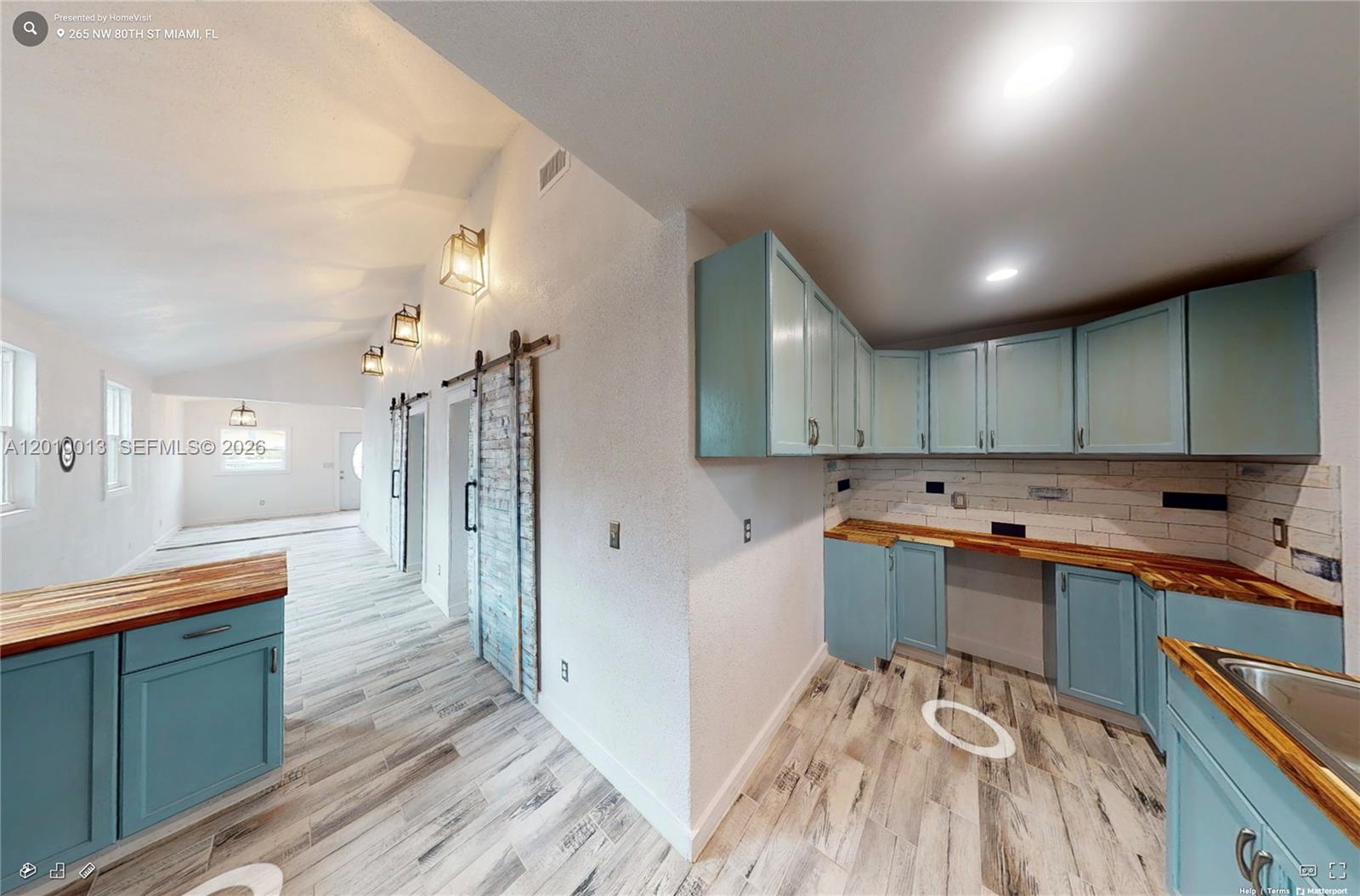 A kitchen features light blue cabinets, wood countertops, and wood-look tile flooring — 265 NW 80th St, Miami FL 33150, MIAMI, FL
