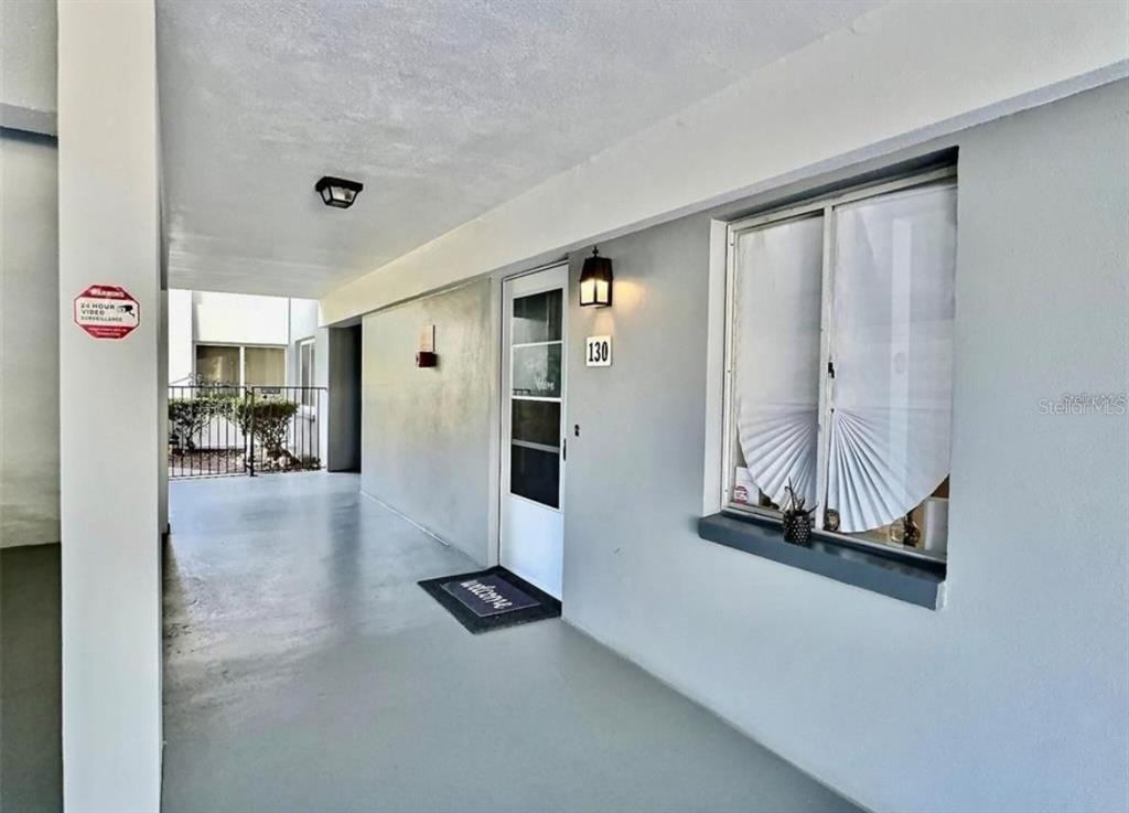 An exterior view of a covered walkway leading to a front door numbered 130 — 8651 10TH STREET N UNIT 130, ST PETERSBURG, FL