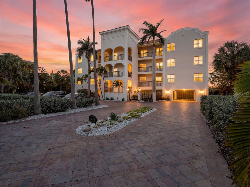 An aerial view of a multi-story white beachside apartment building at sunset — 3110 1ST STREET W UNIT 101, ST PETE BEACH, FL