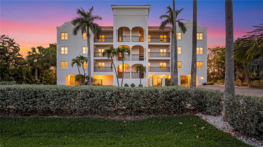 A multi-story apartment building with arched balconies and a paved driveway at sunset — 3110 1ST STREET W UNIT 101, ST PETE BEACH, FL