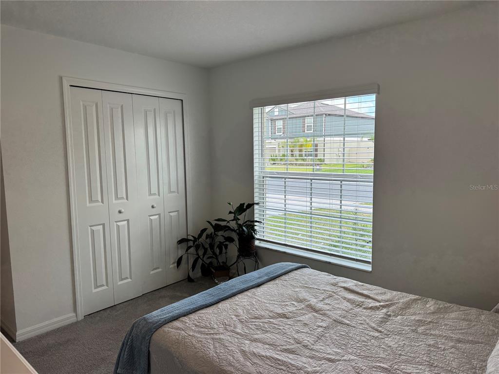 A bedroom features a white closet, a window with blinds, and a bed with bedding — 12218 RADIANT GEM TRAIL, PARRISH, FL