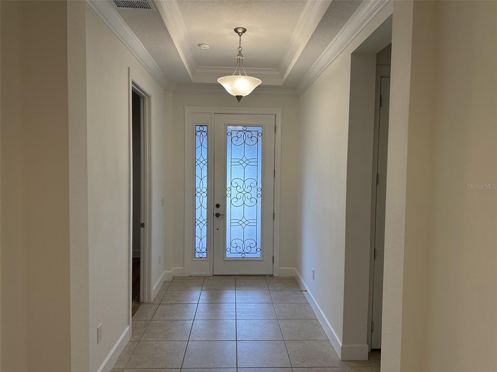 A tiled entryway features a white front door with decorative glass and a tray ceiling — 1355 ZEEK RIDGE STREET, CLERMONT, FL