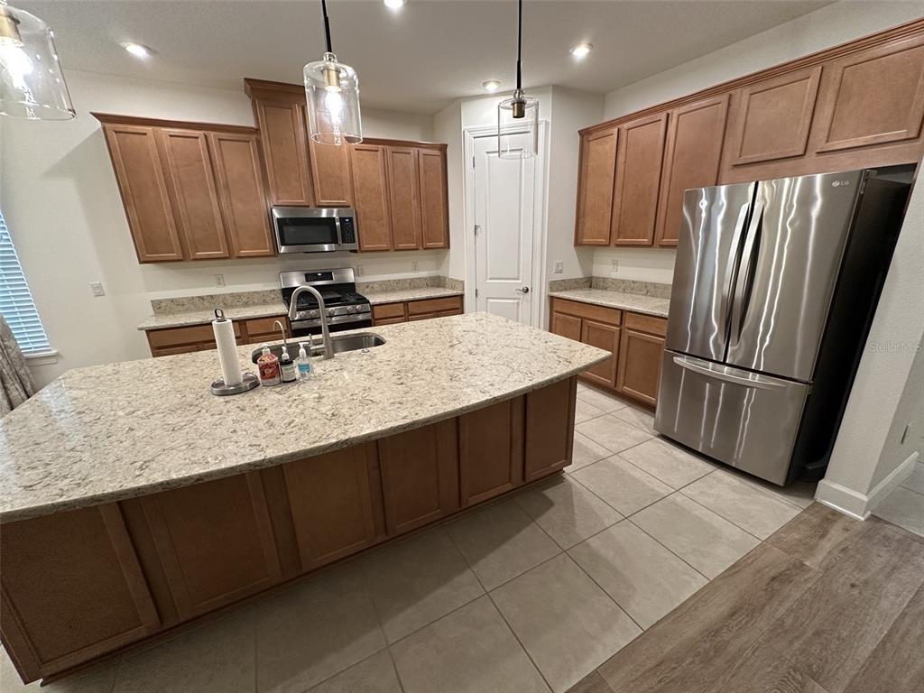 A kitchen features wood cabinets, granite countertops, a central island, and stainless steel appliances — 1355 ZEEK RIDGE STREET, CLERMONT, FL