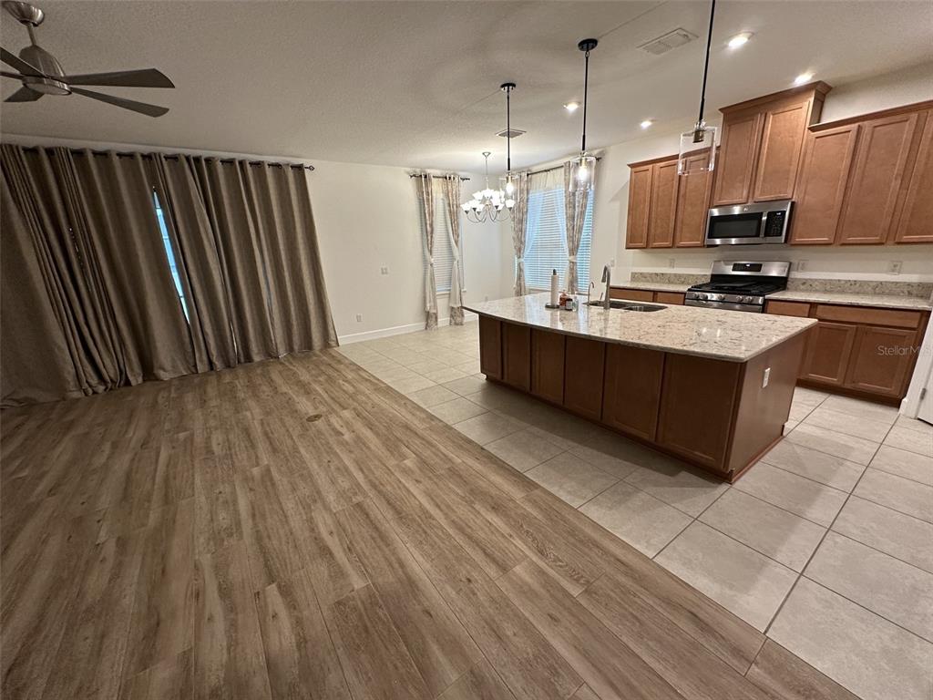 An open-concept kitchen with a large island and wood-look flooring flows into a living area — 1355 ZEEK RIDGE STREET, CLERMONT, FL