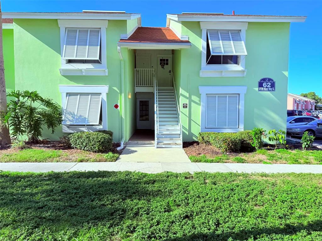 A two-story light green apartment building with white shutters and an exterior staircase — 3735 42ND WAY S UNIT E, ST PETERSBURG, FL