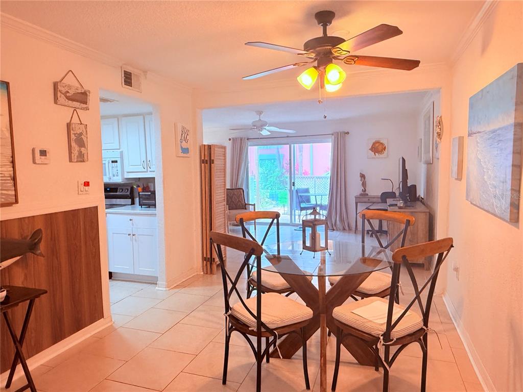 A dining area with a glass table and four chairs sits before a sliding glass door — 3735 42ND WAY S UNIT E, ST PETERSBURG, FL