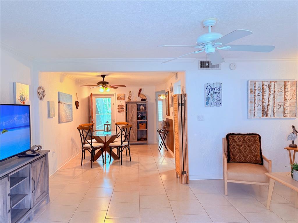 A living and dining area with tile flooring, a ceiling fan, and coastal-themed wall decor — 3735 42ND WAY S UNIT E, ST PETERSBURG, FL