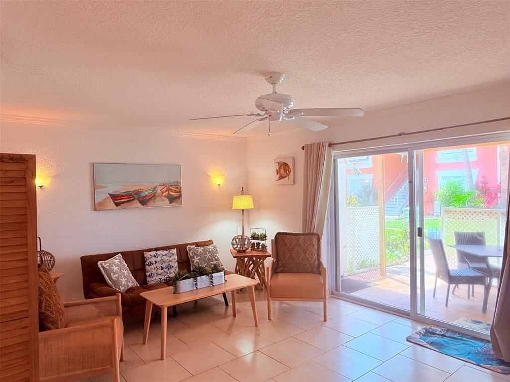 A living room features a brown sofa, two armchairs, a coffee table, and sliding glass doors — 3735 42ND WAY S UNIT E, ST PETERSBURG, FL