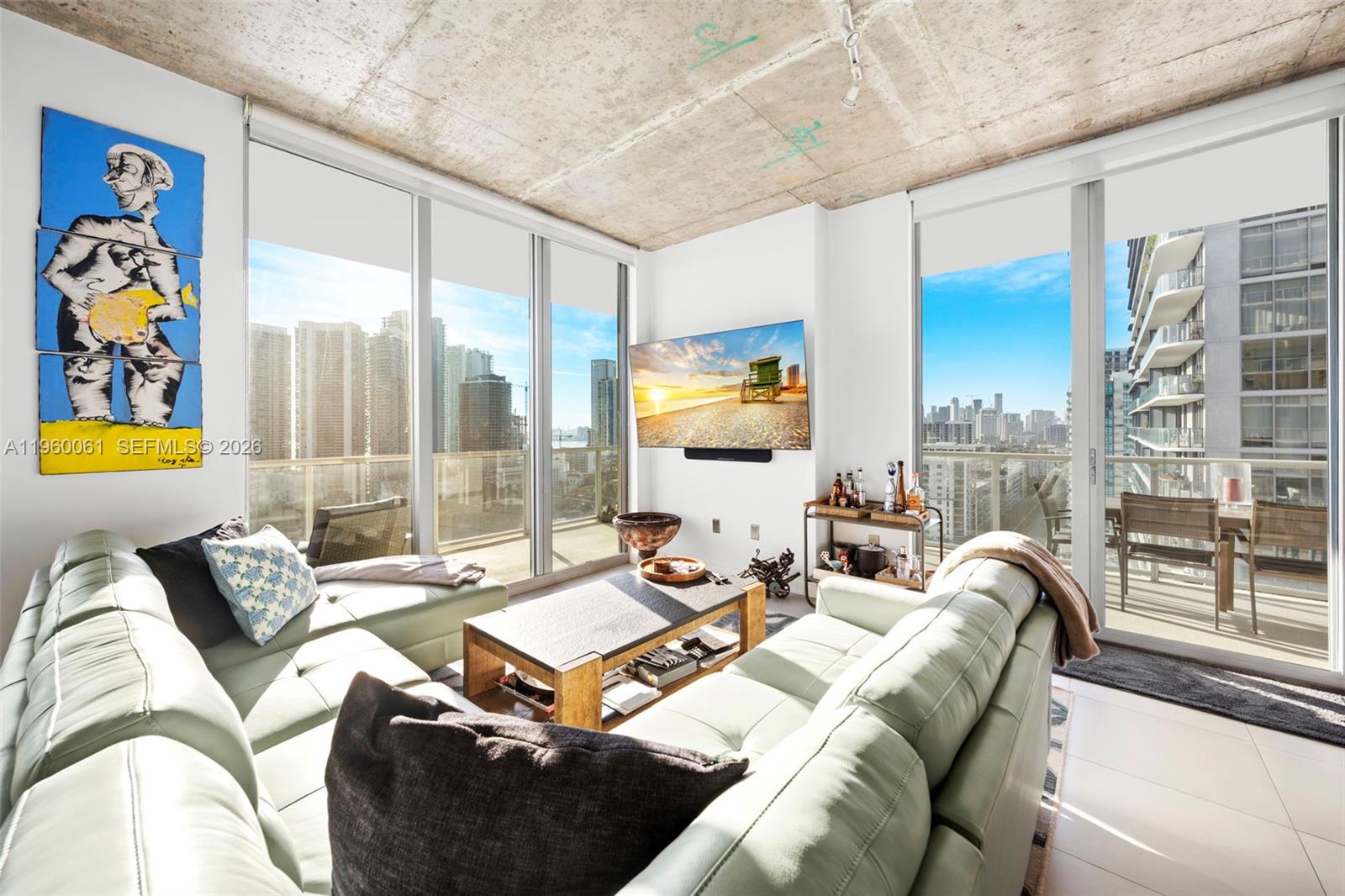 A living room features a concrete ceiling, floor-to-ceiling windows, and a sectional sofa — 3470 E Coast Ave # H2009, Miami FL 33137, MIAMI, FL