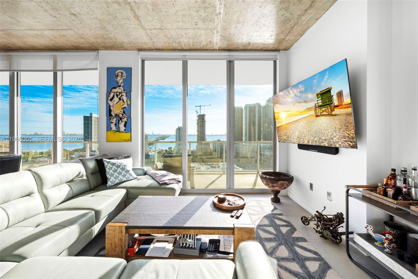 A modern living room features a sectional sofa, a coffee table, and a wall-mounted television — 3470 E Coast Ave # H2009, Miami FL 33137, MIAMI, FL
