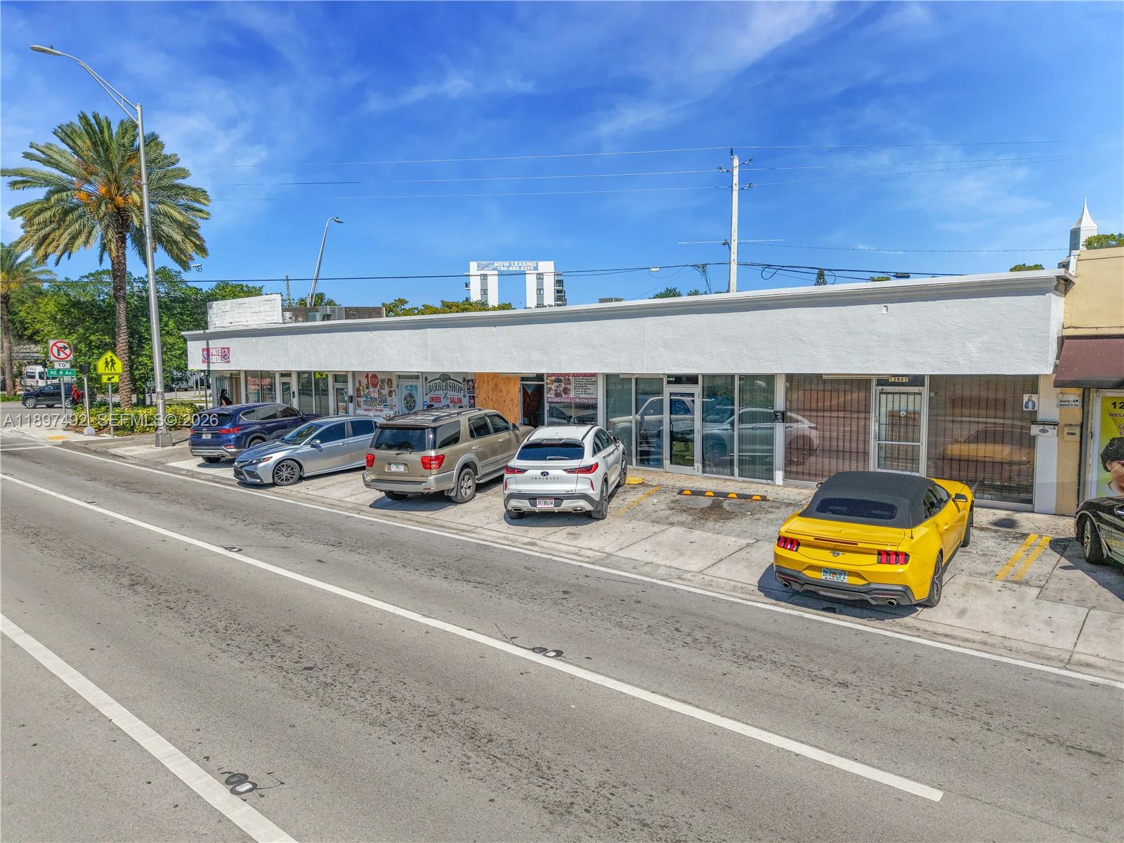 An exterior view of a single-story commercial strip mall with parked cars in front — 12985 W Dixie Hwy, North Miami FL 33161, NORTH MIAMI, FL