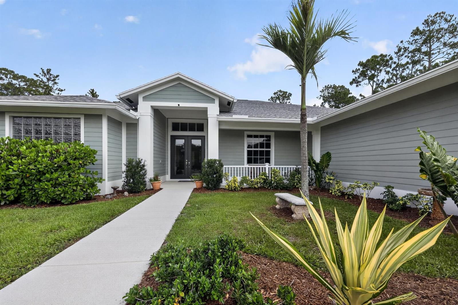 A single-story house with gray siding, a white front porch, and a concrete walkway — 11525 157th Place N, Jupiter FL 33478, JUPITER, FL