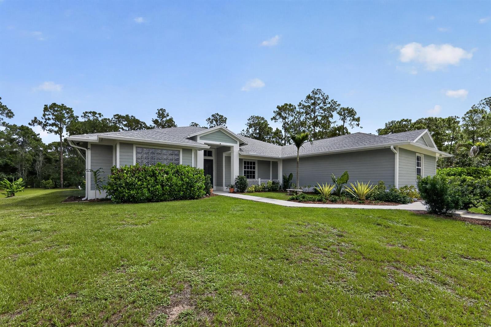 A single-story gray house with a gabled roof sits on a grassy lawn — 11525 157th Place N, Jupiter FL 33478, JUPITER, FL