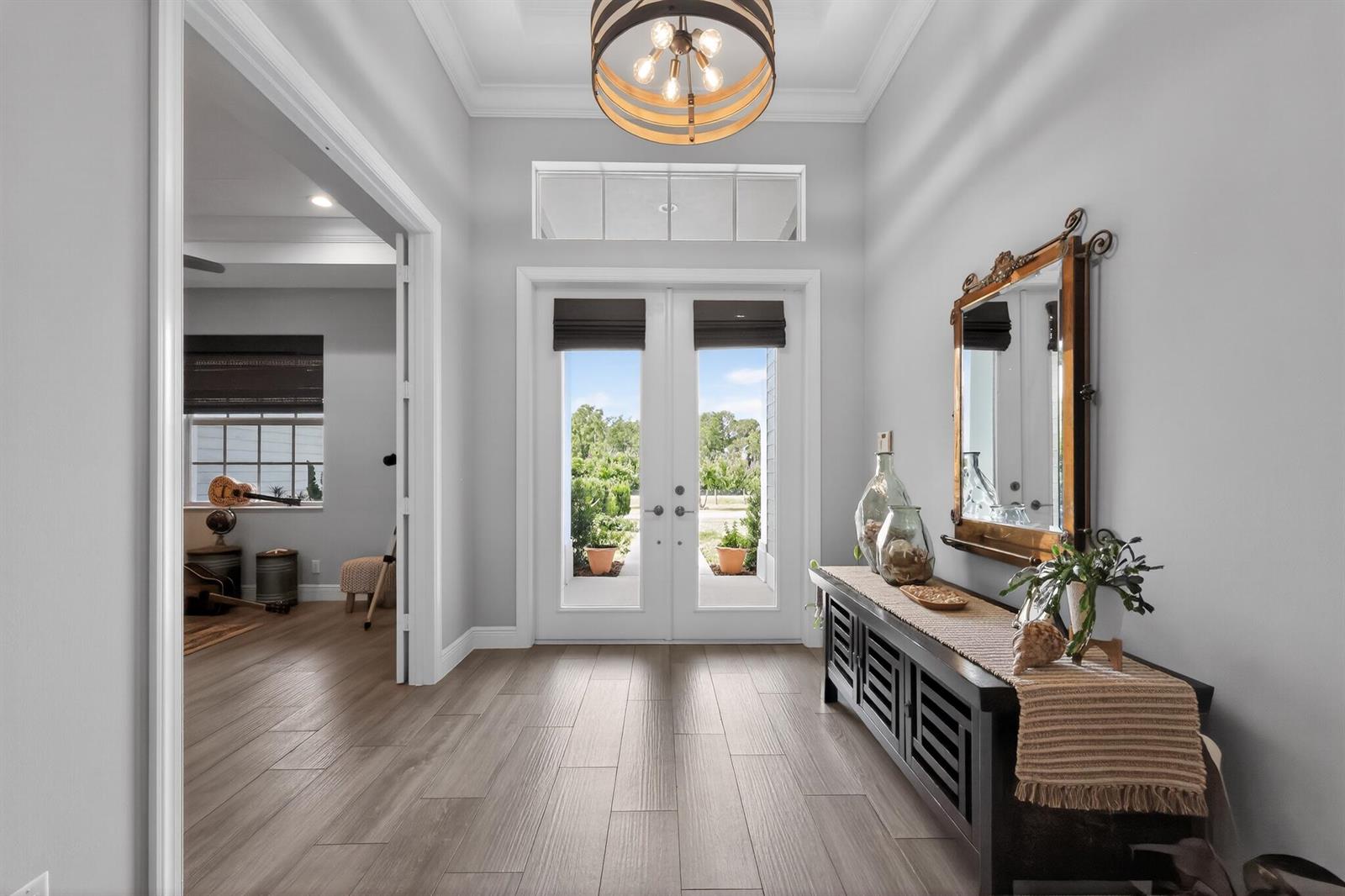 A bright entryway features wood-look tile floors, a dark console table, and double glass doors — 11525 157th Place N, Jupiter FL 33478, JUPITER, FL