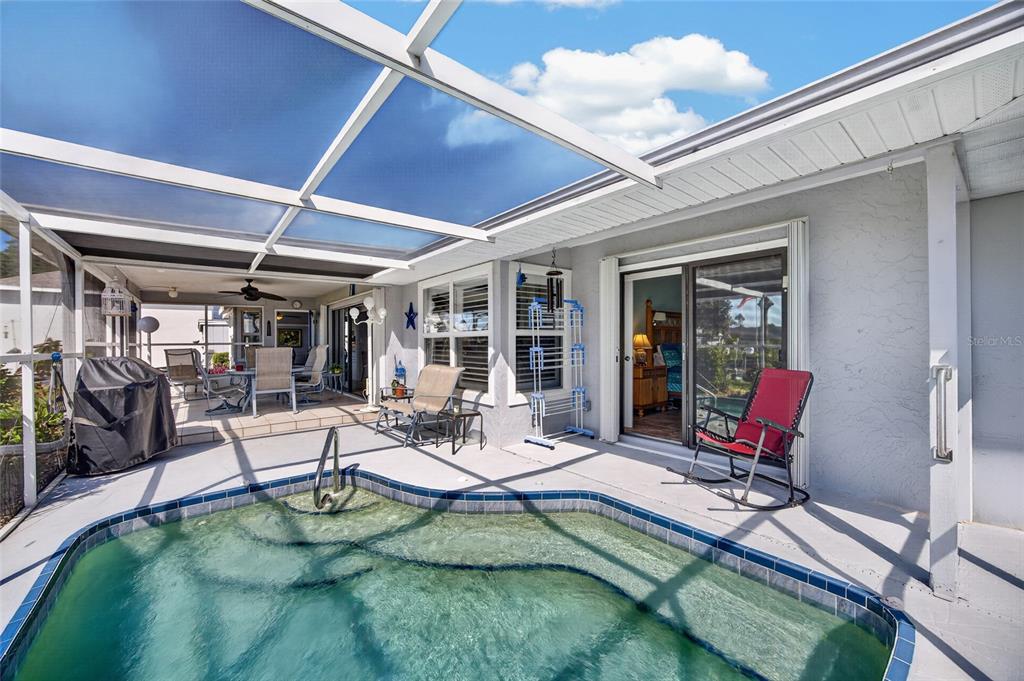 A screened-in patio features a small swimming pool, outdoor furniture, and sliding glass doors — 2516 DIXON TERRACE, PORT CHARLOTTE, FL