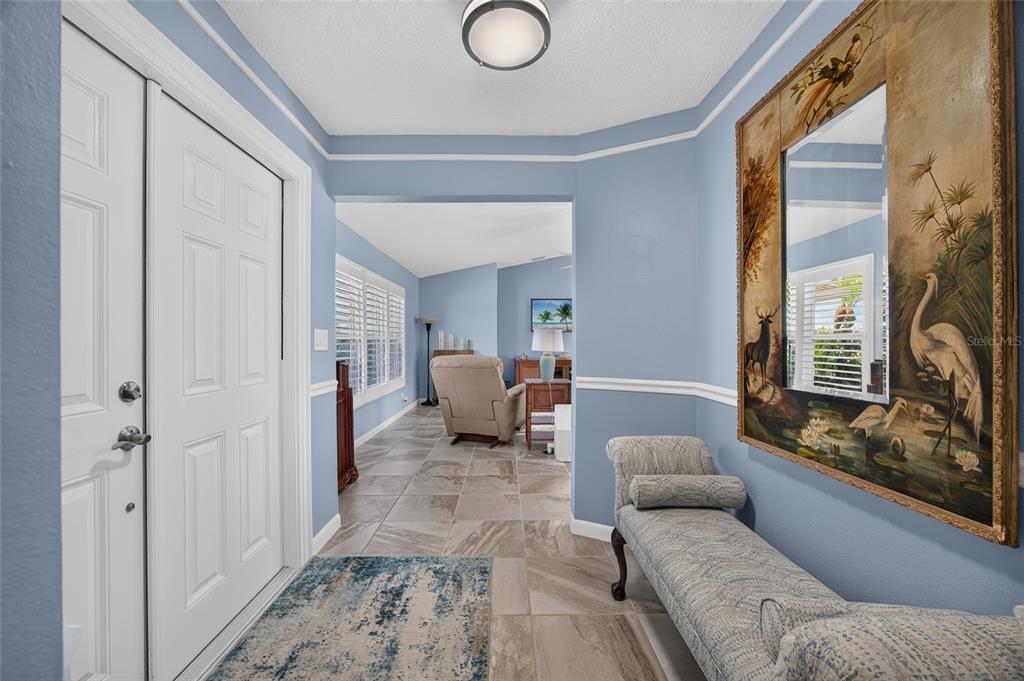 An entryway with blue walls, tile flooring, a bench, and a large decorative mirror — 2516 DIXON TERRACE, PORT CHARLOTTE, FL