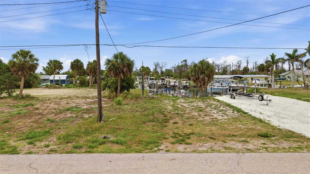 A vacant waterfront lot features palm trees, a boat slip, and a gravel driveway — 1949 PENNSYLVANIA AVENUE UNIT BL1, ENGLEWOOD, FL