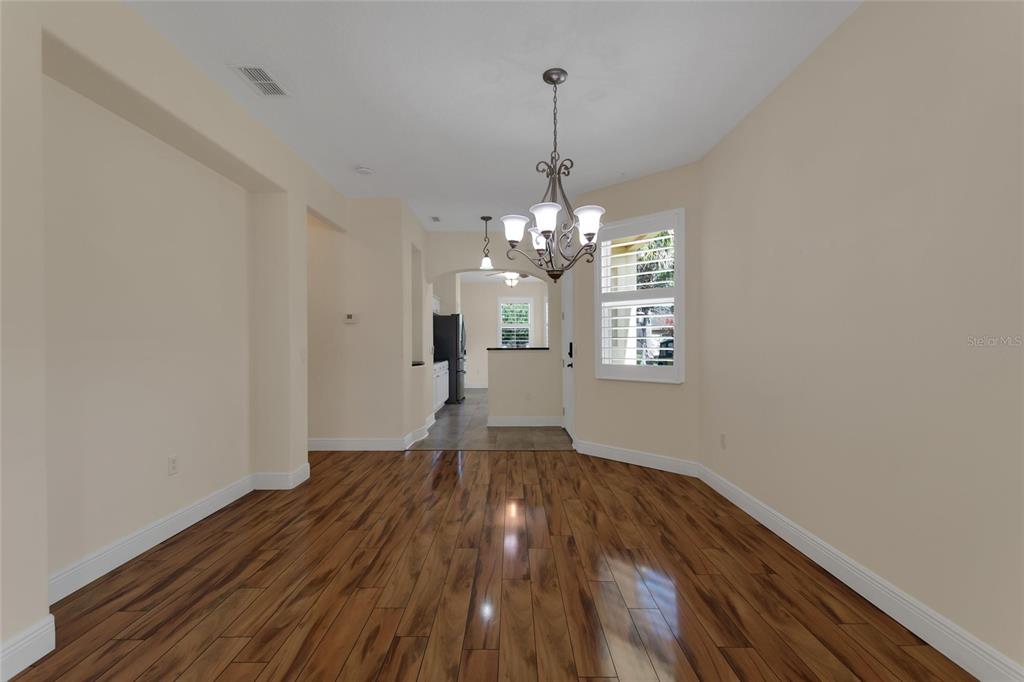 A dining room with wood-look flooring, a chandelier, and a view into the kitchen — 624 GRAND CANAL DRIVE, KISSIMMEE, FL