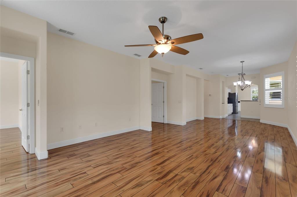 A spacious living area features hardwood floors, a ceiling fan, and an adjacent dining space — 624 GRAND CANAL DRIVE, KISSIMMEE, FL
