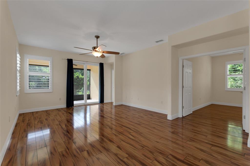 A spacious room with wood-look flooring, a ceiling fan, and sliding glass doors to a patio — 624 GRAND CANAL DRIVE, KISSIMMEE, FL