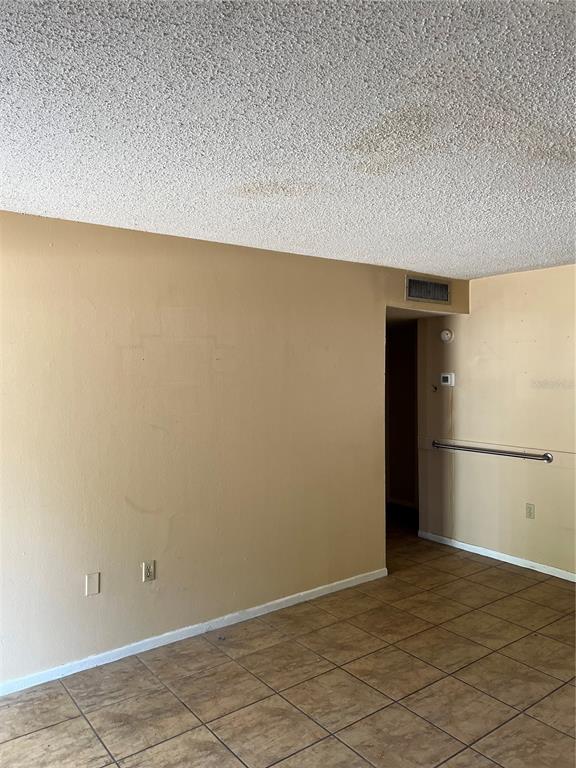 An interior view of a room with tan walls, tiled floors, and a textured ceiling — 800 N FISKE BOULEVARD UNIT 606, COCOA, FL