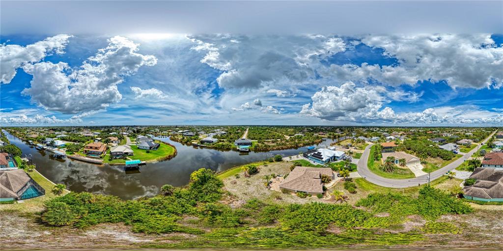 An aerial panoramic view of a residential neighborhood featuring houses along a canal — 15304 HENNIPEN CIRCLE, PORT CHARLOTTE, FL