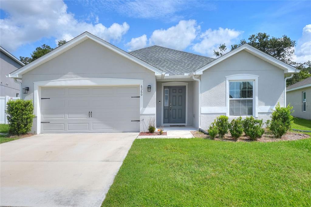 A single-story house with a gray garage, a dark front door, and a grassy lawn — 6360 GARDNER DRIVE, LAKELAND, FL